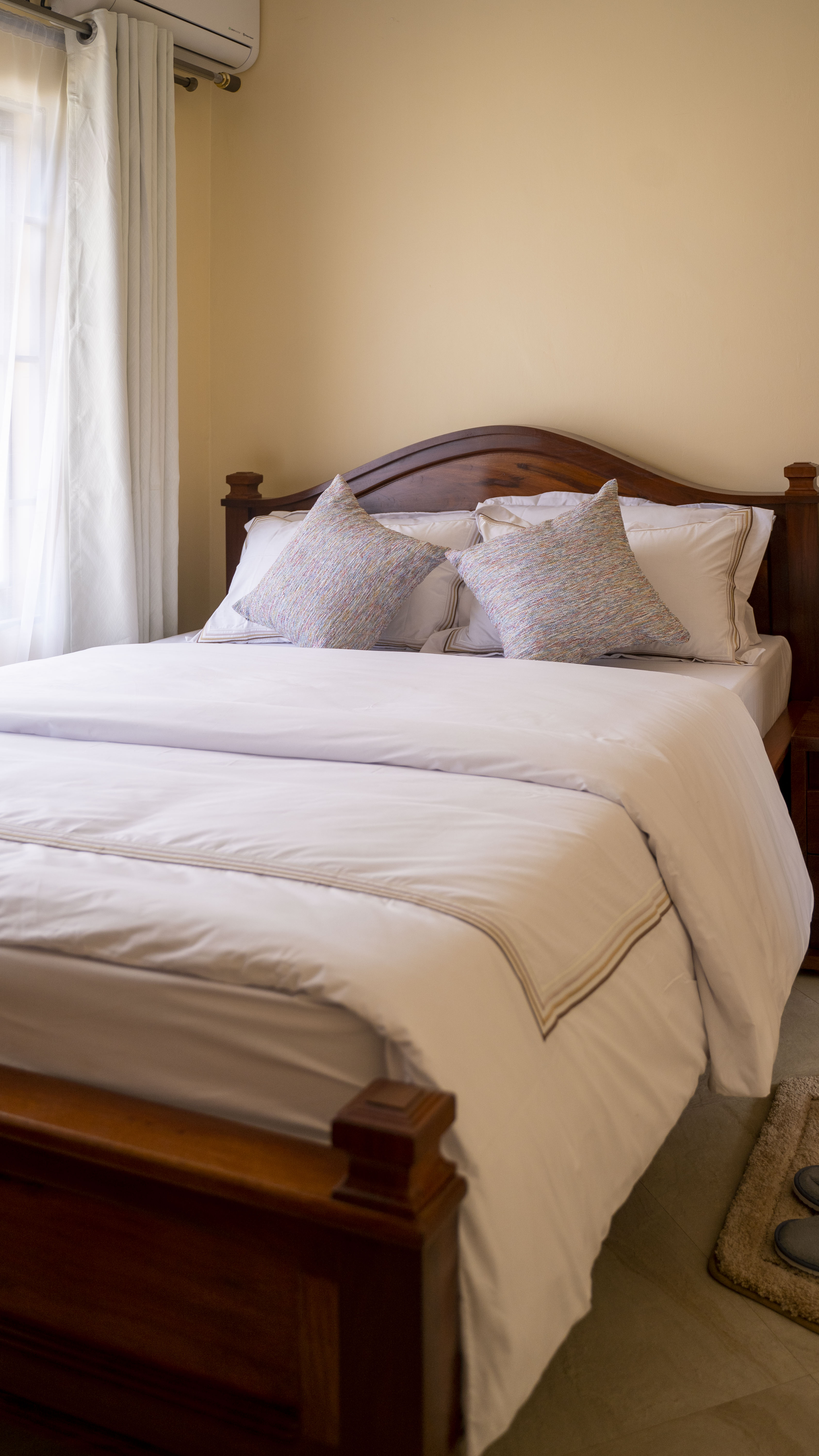 Guest bedroom — teak bed frame and freshly pressed white Egyptian-cotton linens